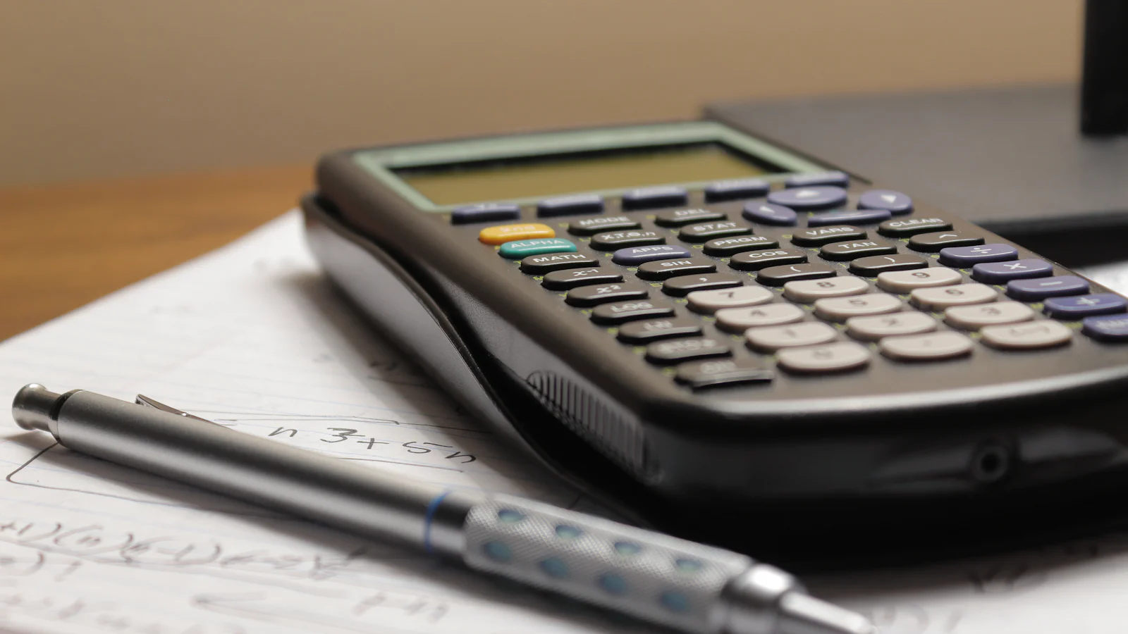 Calculadora e caneta sobre folha de papel com anotações