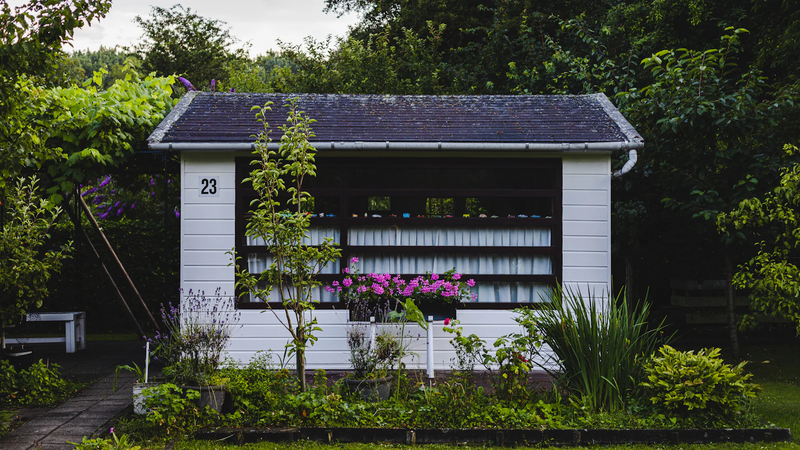 Pequena casa branca cercada por jardim e plantas